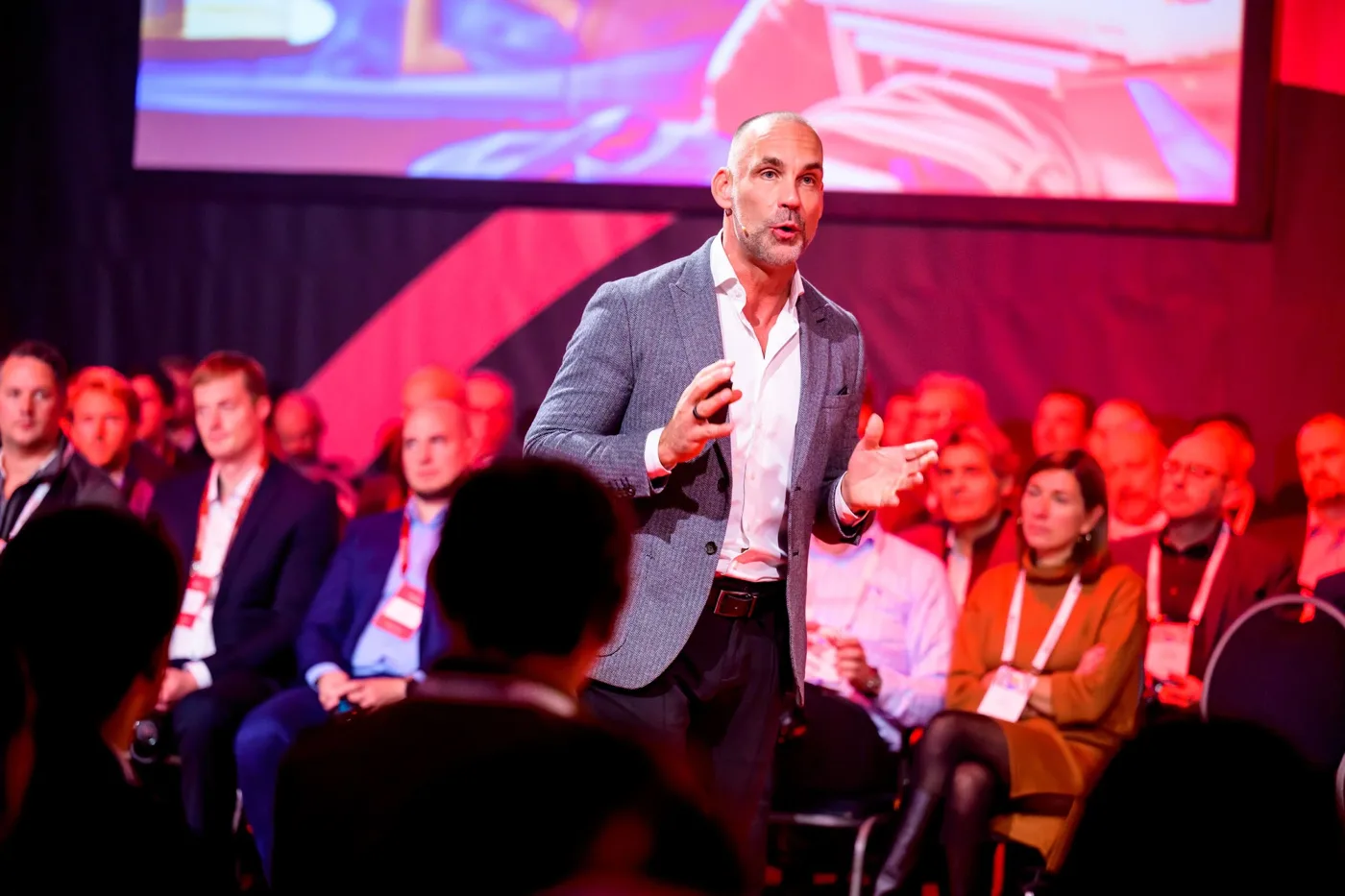 Richard van Hooijdonk in grijs colbert spreekt midden tussen zittende congresgangers met badges